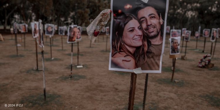 The massacre at Nova music festival site with photos of victims on poles in the field.