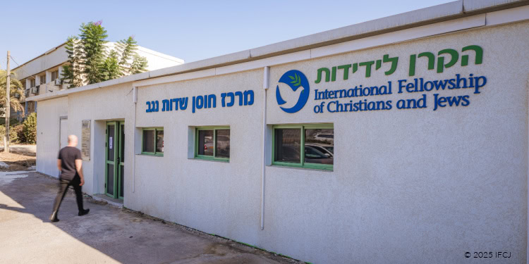 Day with Tamir Idan, Head of the Sdot Negev Regional Council - Resilience Center - Sdot Negev, Israel - August 21, 2025 man in black walking into white building, one story, Hebrew letters in blue, IFCJ logo