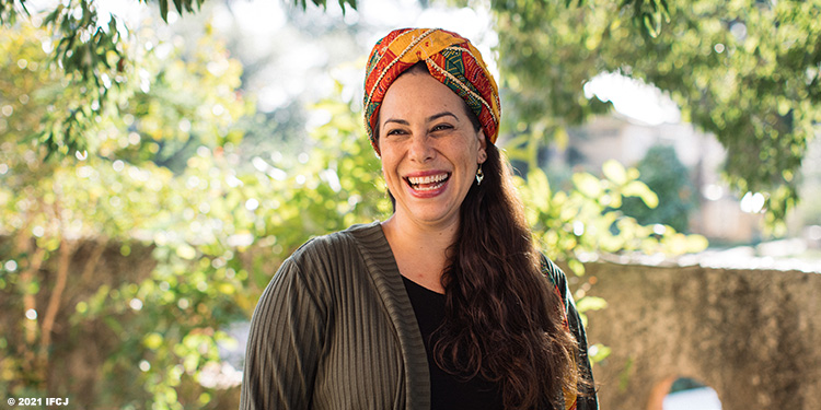 Yael Eckstein with scarf on her head smiling and celebrating Purim.