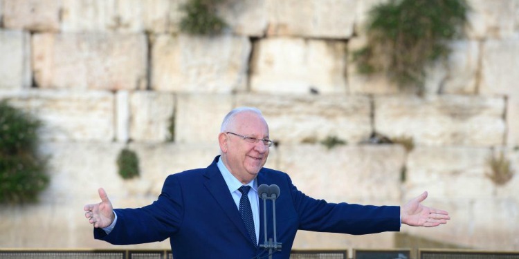 President Rivlin with his arms outstretched as he's talking at a podium by the Western Wall.