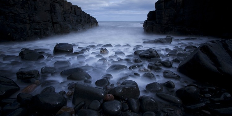 Fog running over rocks during dusk.