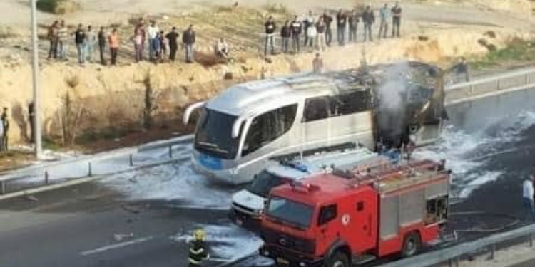 A bus hit by a rocket parked next to two emergency vehicles.