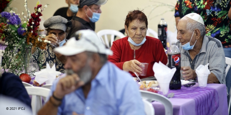 Elderly Jewish couple enjoying Rosh Hashanah Meal together with others in a banquet style meal.