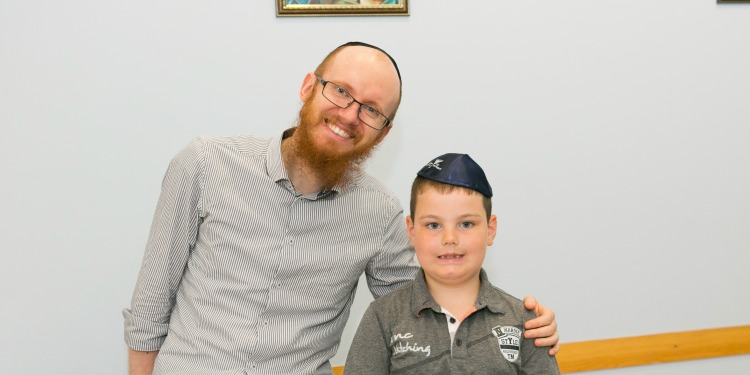 A man and young boy smiling, standing next to each other.