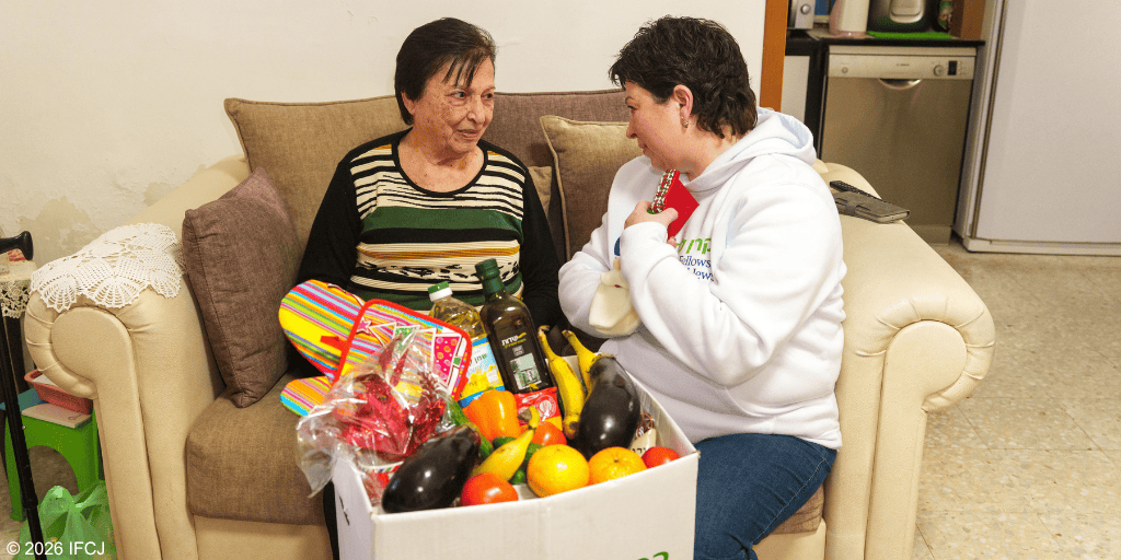 A woman and a young girl sharing a heartfelt moment with a box of fresh fruits and vegetables, symbolizing kindness and healing.