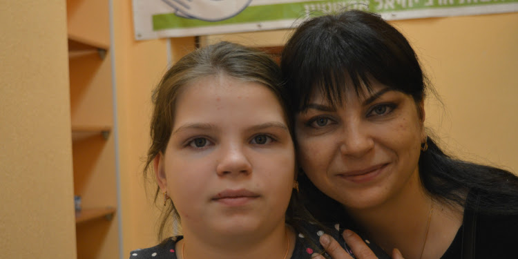 Angelina Anisimova and her daughter looking directly at the camera.