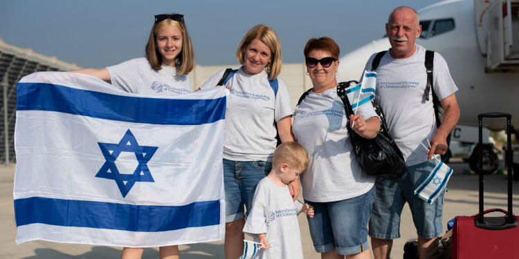 Family of five holding up the Israeli flag as they just made Aliyah.