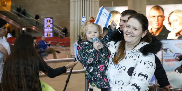 Mother holding her child who's holding an Israeli flag.