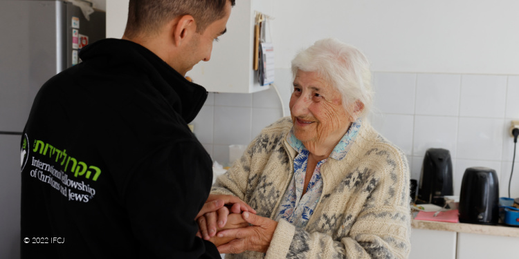 IFCJ staff member holding the hands of an elderly Jewish woman.
