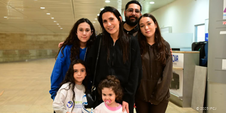 Cynthia and Yoni Abitbul Family - Freedom Flight from France - Tel Aviv, Israel - December 10, 2025 Cynthia and Yoni Abitbul with 4 daughters: Shany (15 years), Liv (11 years), Ness (6 years), Abby (2 years) standing in a group at the airport, smiling at the camera - young girl (Abby) with pacifier wearing branded logo T-shirt and holding small Israeli flag - girl (Ness) wearing branded logo T-shirt