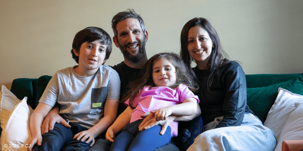 Happy family with two children and parents sitting together on a sofa, smiling and enjoying a moment of togetherness, representing unity and blessings.
