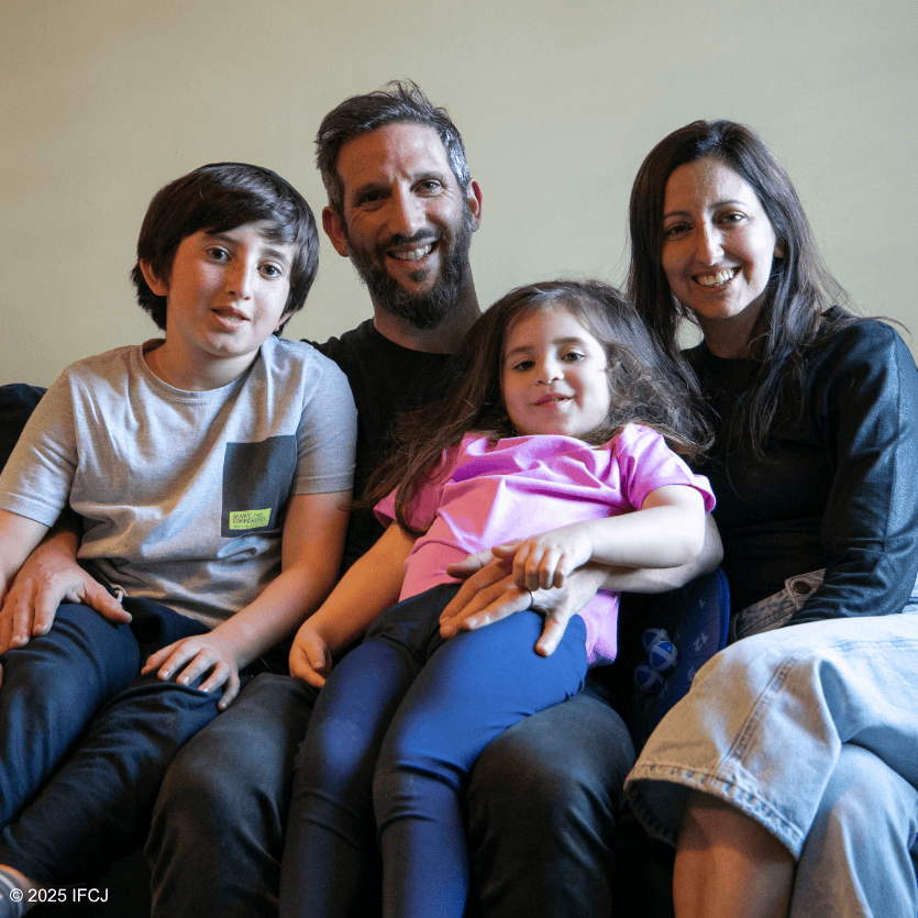 Happy family with two children and parents sitting together on a sofa, smiling and enjoying a moment of togetherness, representing unity and blessings.