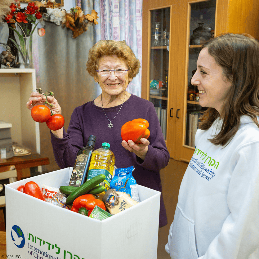 Older woman and young woman with vegetables in a home setting.