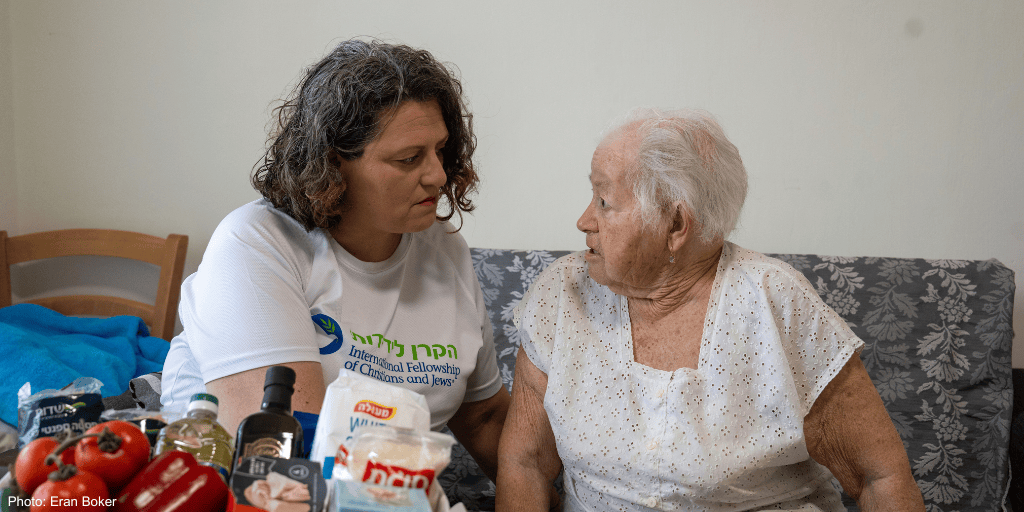 A caregiver providing compassionate support to an elderly woman in a cozy home setting, highlighting community and humanitarian aid efforts.