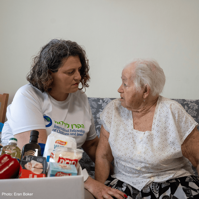 A caregiver providing compassionate support to an elderly woman in a cozy home setting, highlighting community and humanitarian aid efforts.