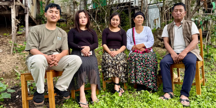 Family group sitting outdoors in a garden, symbolizing hope, resilience, and community support through IFCJ programs.