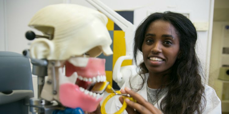 Ester smiling at the camera while working on a fake skull in a lab.