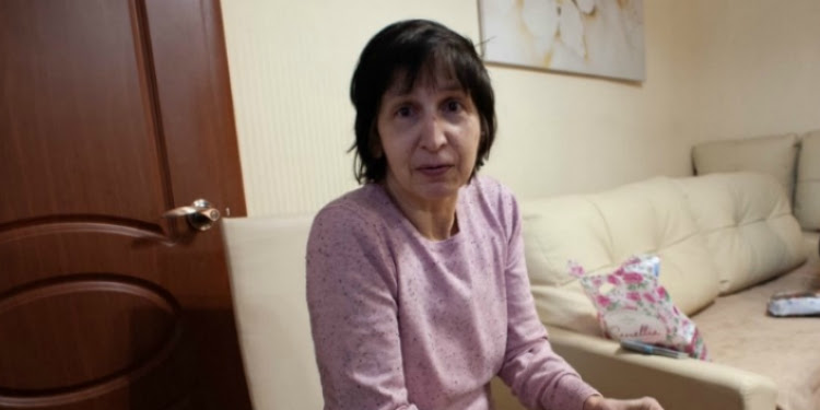 Jewish woman sitting on a white couch looking directly into the camera.