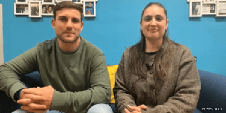 Jared Michelow and Jamie Seid, olim from South Africa. adult couple sitting on couch, adult man, green long sleece shirt, fingers laced, adult woman, brown cardigan, smiling, happy