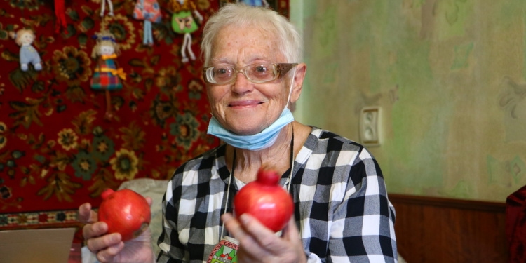Elderly Jewish woman holds pomegranates in her hands from High Holy Days food box