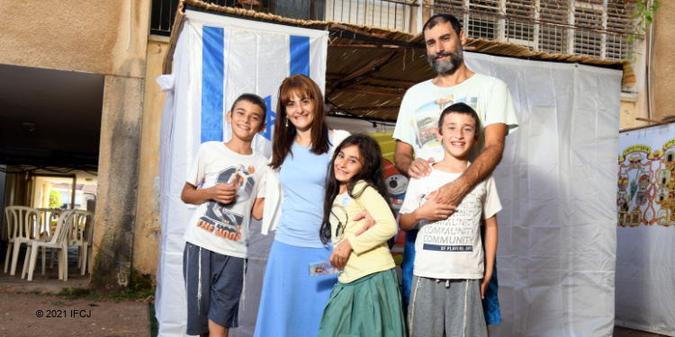 Family of 5 standing in front of an Israeli flag.