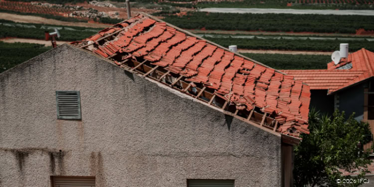 A building with a damaged roof and ongoing construction work, highlighting IFCJ's efforts in providing humanitarian aid and rebuilding communities in need.