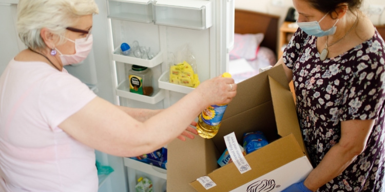 Chamah social worker helping elderly woman put products from IFCJ food box into refrigerator