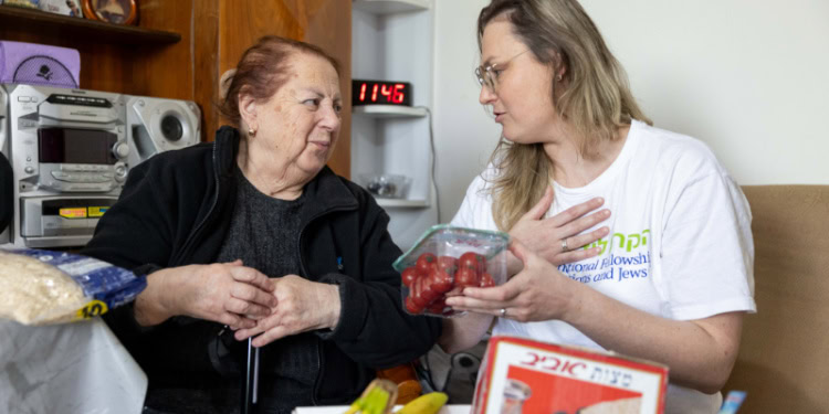 Elderly Holocaust survivor receives matzah and a Passover food box.
