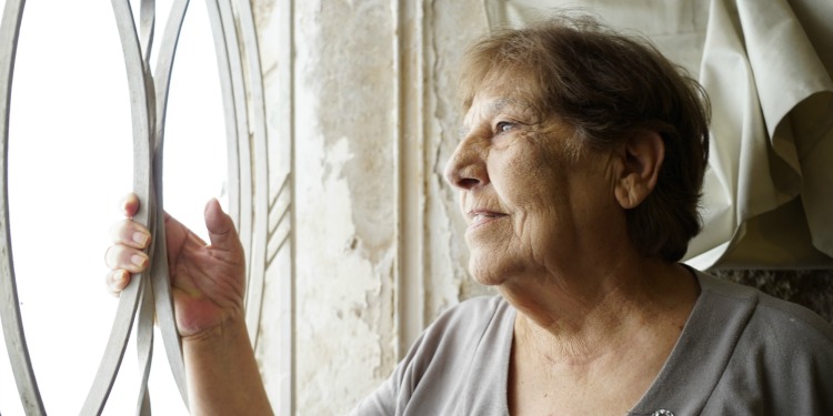 Elderly Jewish woman smiling into the distance out of a window.