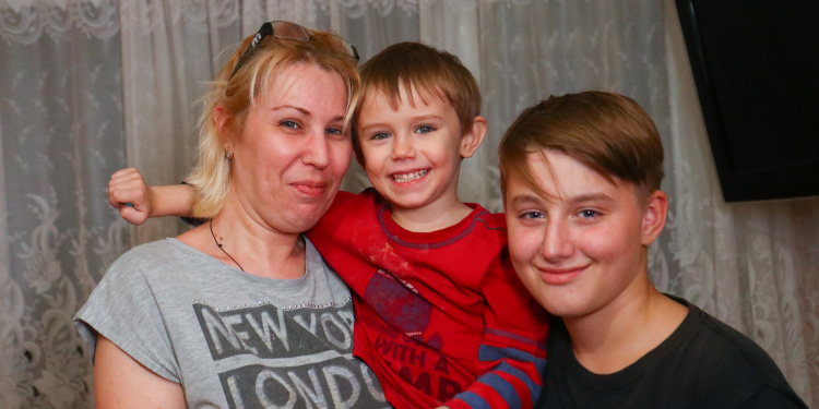 Family of three smiling at the camera.