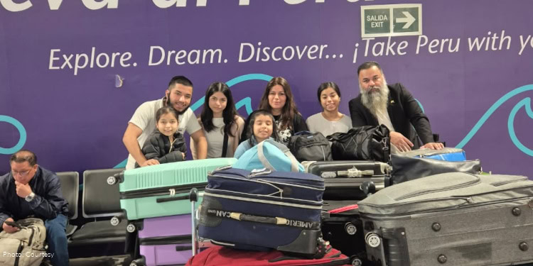 The Paniagua Family from Peru at Jorge Chávez International Airport before making aliyah. family, group photo, smiling, happy, luggage carts and bag, purple wall in background.