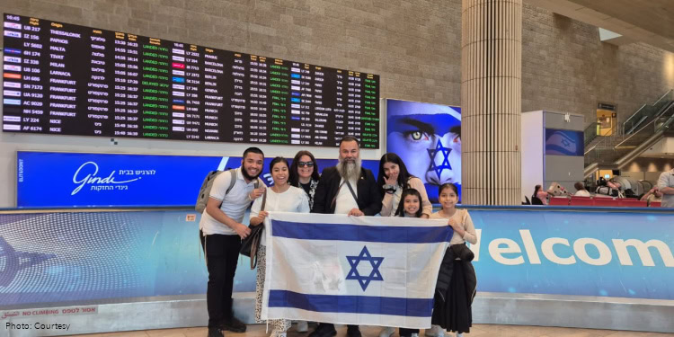 The Paniagua Family from Peru at Ben Gurion International Airport in Tel Aviv.family, group photo, holding Israeli flag, adult man and woman and five children, smiling, happy
