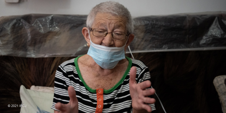 Elderly Jewish woman in a mask motioning with her hands.