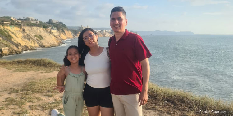 Rubio-Balanta Family - Making aliyah from Colombia on March 17, 2026 famil standing on a seacoast overlooking the ocean - man, red shirt, woman, white tank top and black shorts - girl, light green jumpsuit - smiling at camera