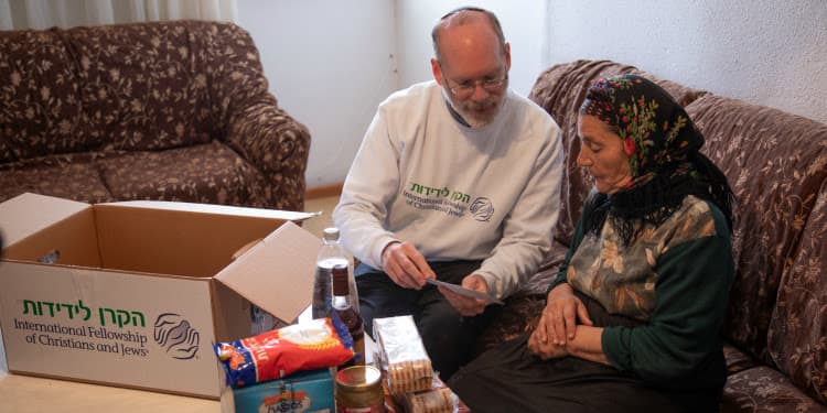 IFCJ volunteer helping a woman with her IFCJ food box.