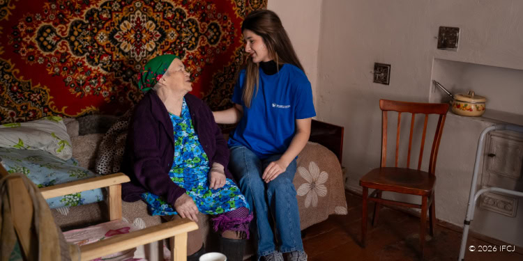 A young woman caring for an elderly woman at home, demonstrating compassion and support, with a warm and inviting living room setting.