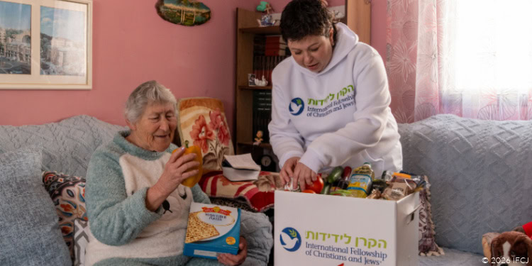 Elderly woman receiving a Passover gift from a young volunteer during a fellowship event, symbolizing gratitude and community support.