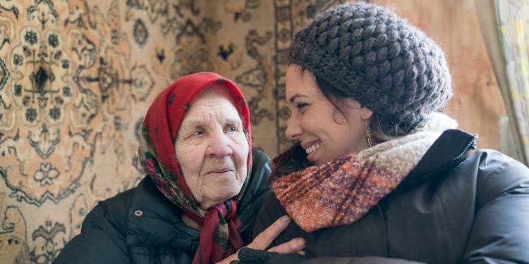 Yael Eckstein sitting with an elderly Jewish woman as they're smiling at eachother.
