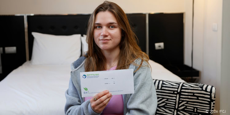 Young woman holding a donation check for IFCJ, symbolizing support for humanitarian aid and charity efforts.