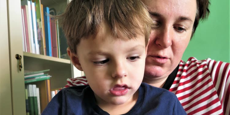 Young boy sitting on his mother's lap.