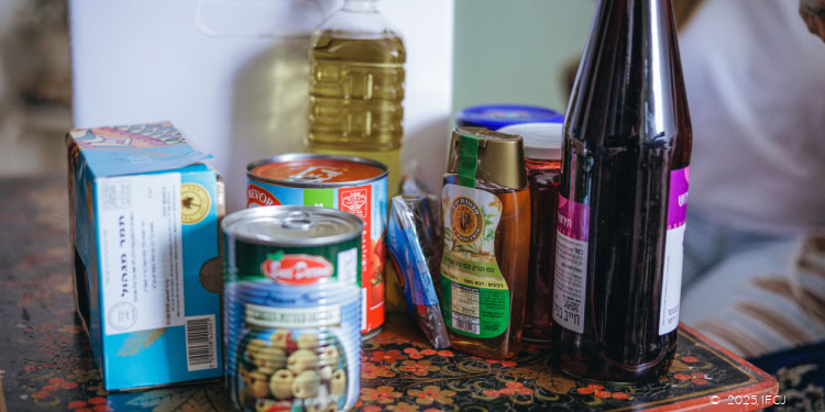 Assorted canned goods, bottled liquids, and food packages on a table, representing charitable aid and community support.