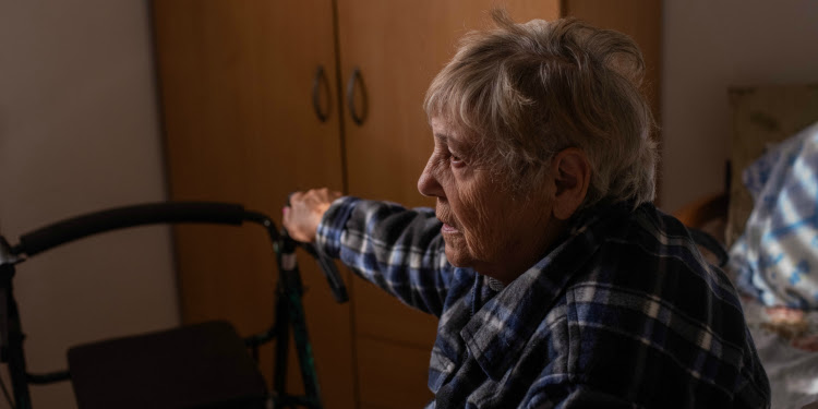 Elderly Jewish woman holding on to her walker while looking into the distance.