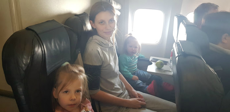 Anastasia sitting on a plane with her two daughters.