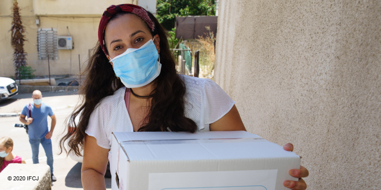 Yael Eckstein wearing a mask and holding a branded logo food box