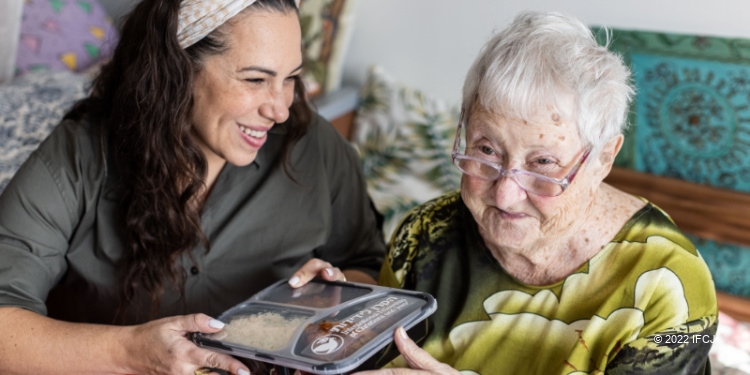Yael Eckstein blessing Yehudit, an elderly woman in Israel, with a food delivery