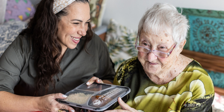 Yael Eckstein blessing Yehudit, an elderly woman in Israel, with a food delivery