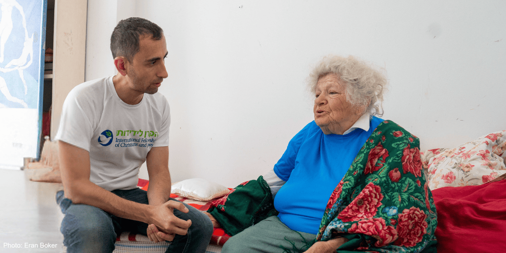 A young man providing compassionate support to an elderly woman in a care setting, highlighting kindness and community service.