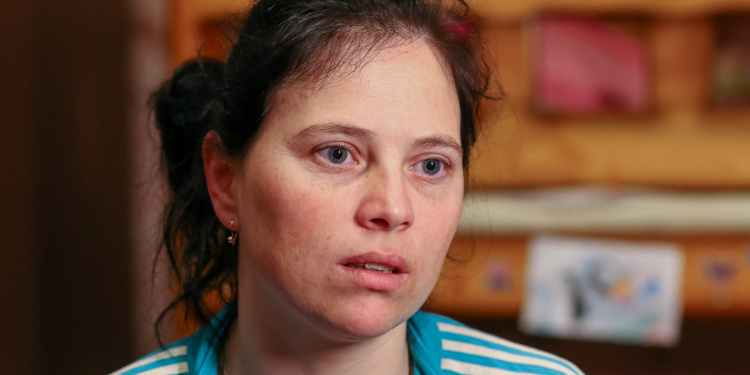 Jewish woman in blue and striped shirt looking into the camera.