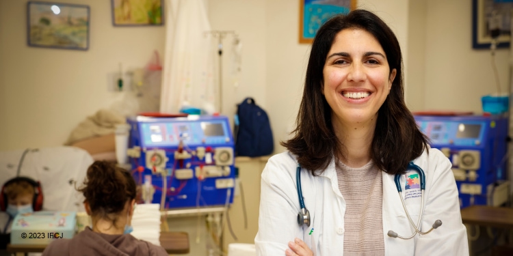 Female doctor at Schneider hospital smiling ahead while a nurse and child are behind her.