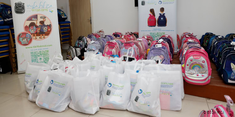 pink and purple backpacks arranged or distribution, white IFCJ-branded tote bags containing school supplies